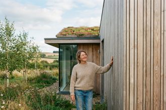 Femme souriante près d'une maison en bois écologique