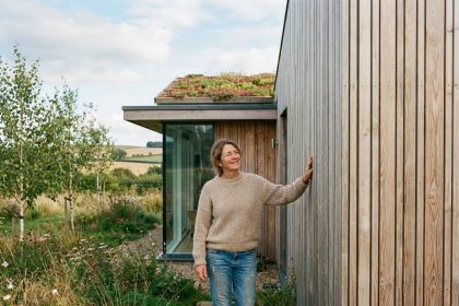 Femme souriante près d'une maison en bois écologique